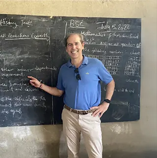 Un colaborador de la fundación junto a la pizarra de un aula de la escuela