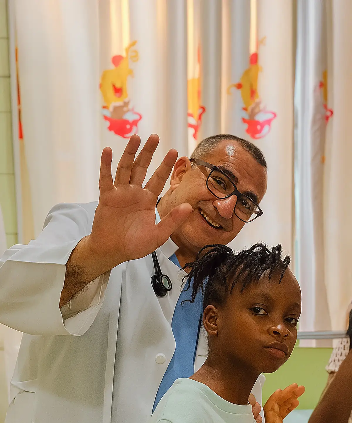 Marlon, el médico de la fundación, saluda junto a una niña del orfanato